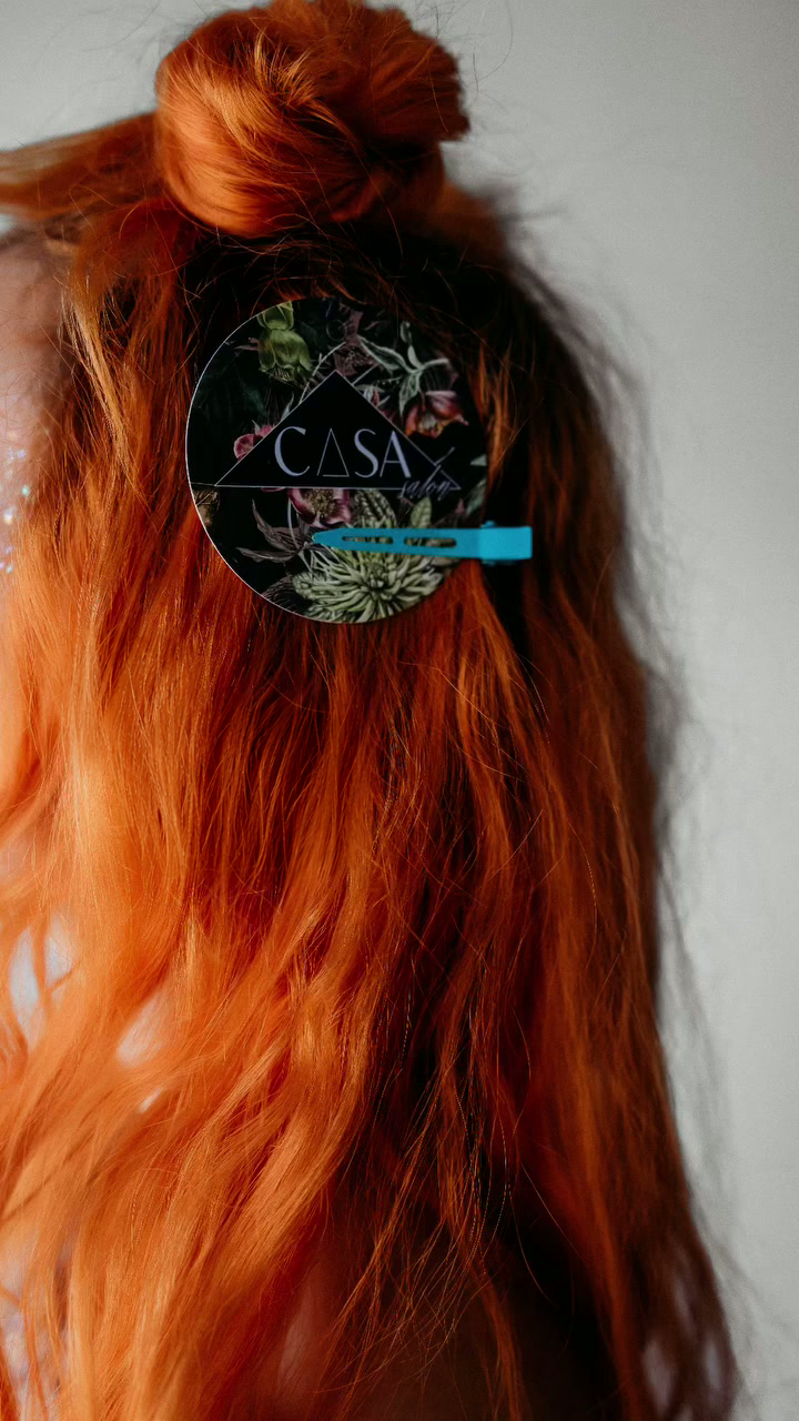 Vivid orange hair pinned with a Casa card